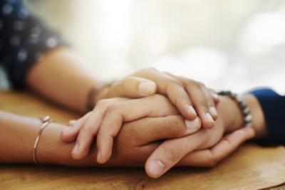 Two people are supporting one another by holding hands. They have light and medium light skin.