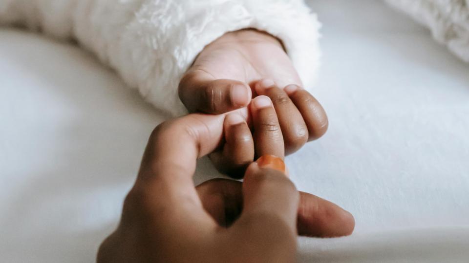A baby's hand grasping their parent's index finger