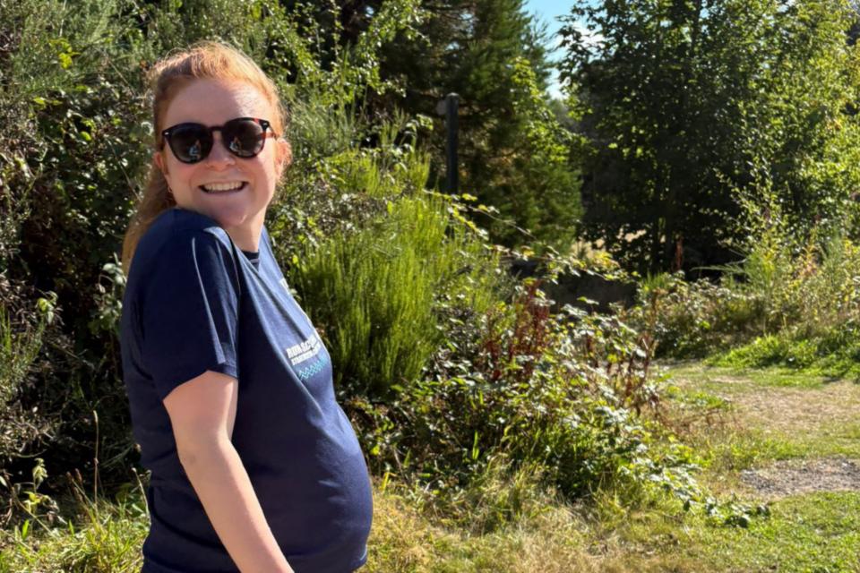 Chloe outdoors wearing sunglasses on a sunny day, smiling at the camera.