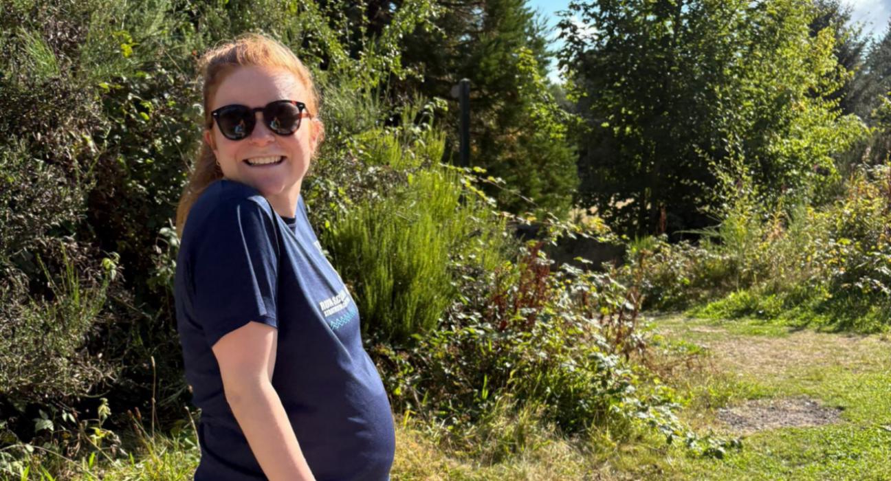 Chloe outdoors wearing sunglasses on a sunny day, smiling at the camera.