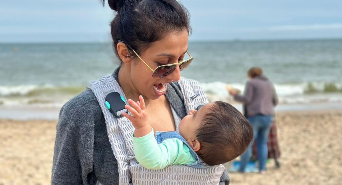 Harpal on the beach with Lara in a carrier.