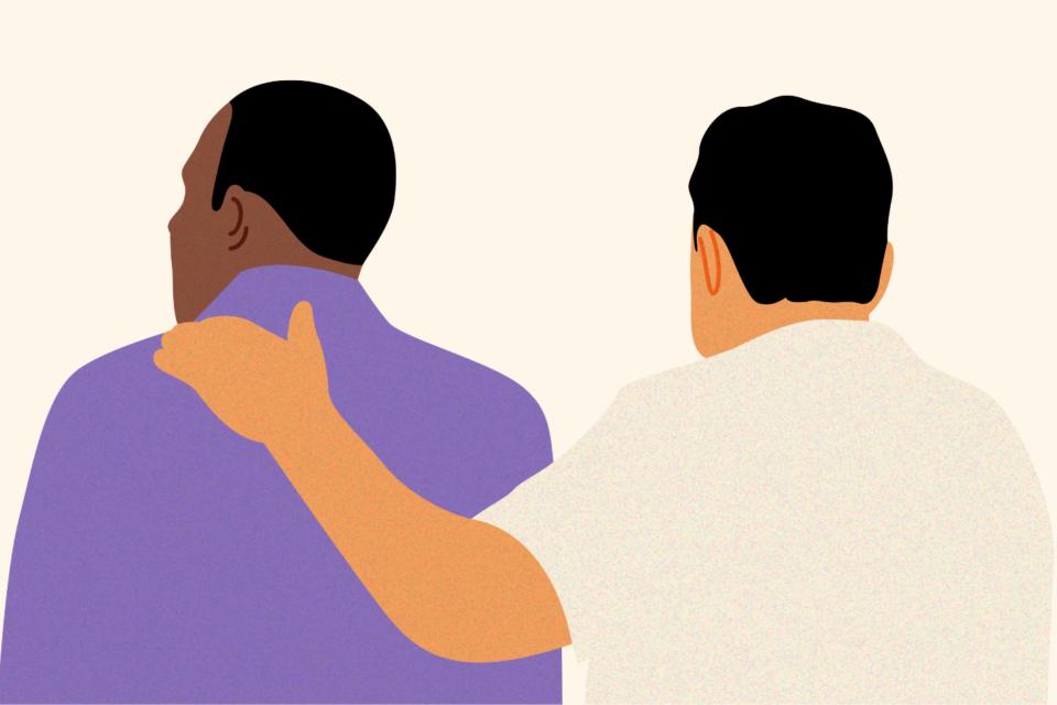 Two men with their back to us. One man has a supportive arm around the other.