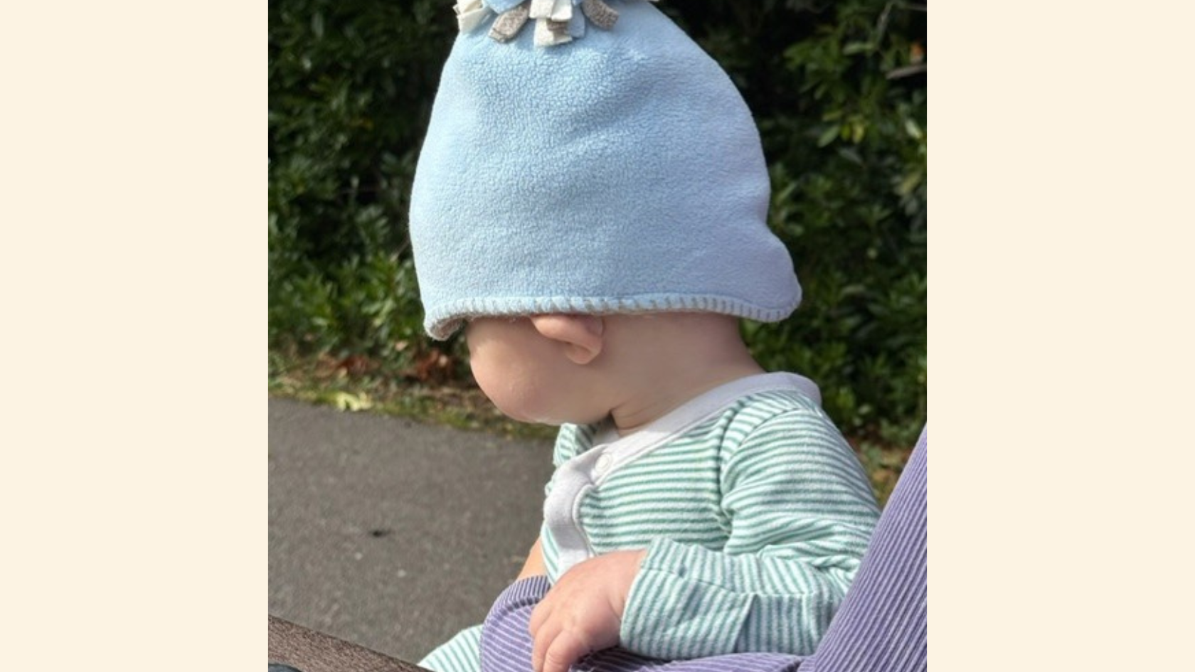 Baby Jonah wearing a blue hat, and a stripy top, facing away from the camera.