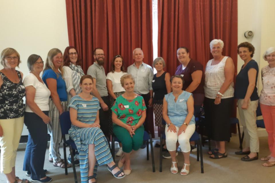 Group of befrienders, some sitting and some standing, all smiling at the camera.