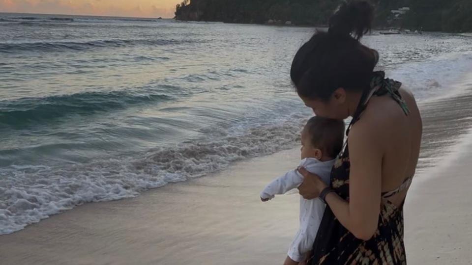 Harpal holding Lara, facing the sea.