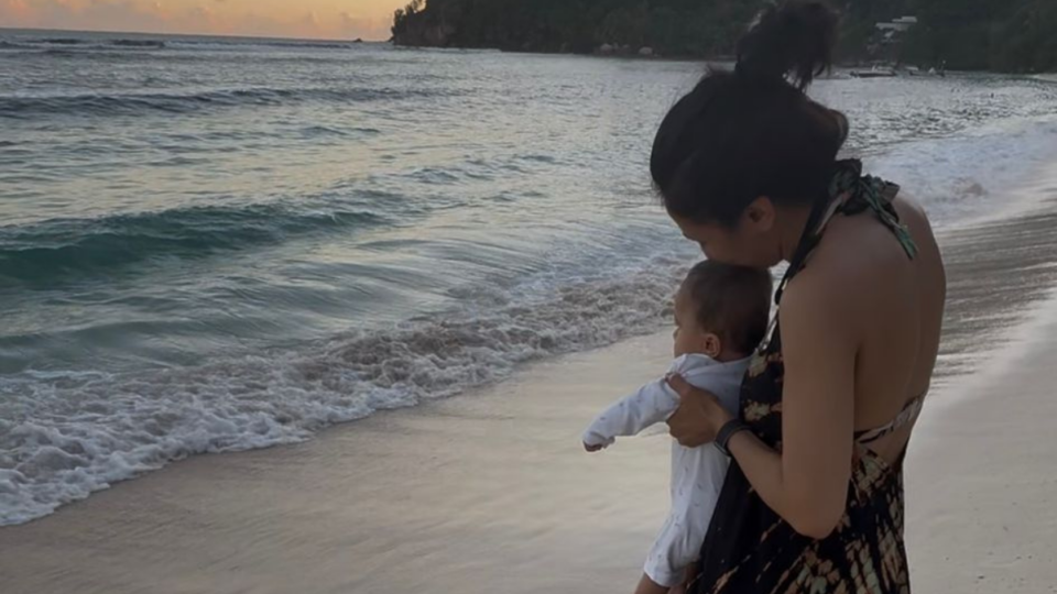 Harpal holding Lara, facing the sea.