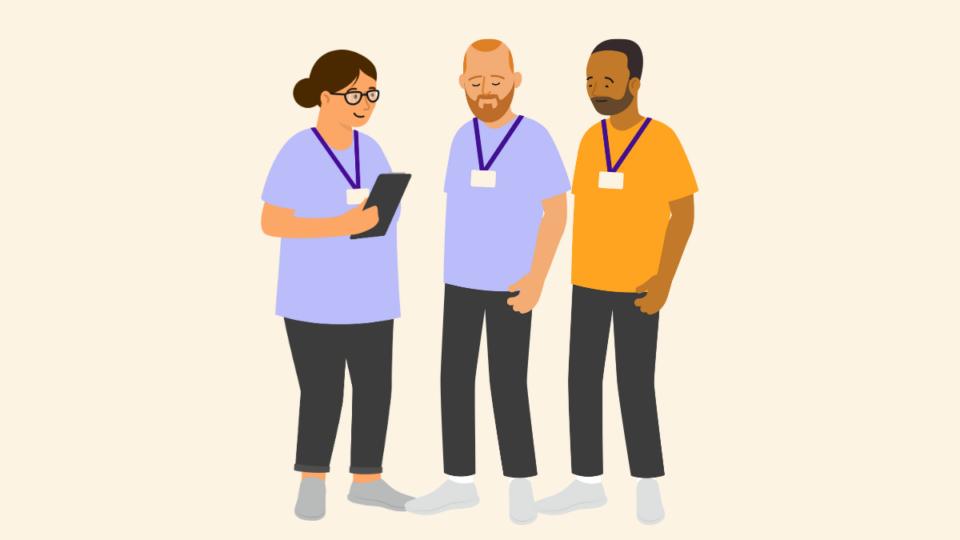 Three people all wearing t-shirts and lanyards, standing next to each other. The lady on the left is holding a clipboard.