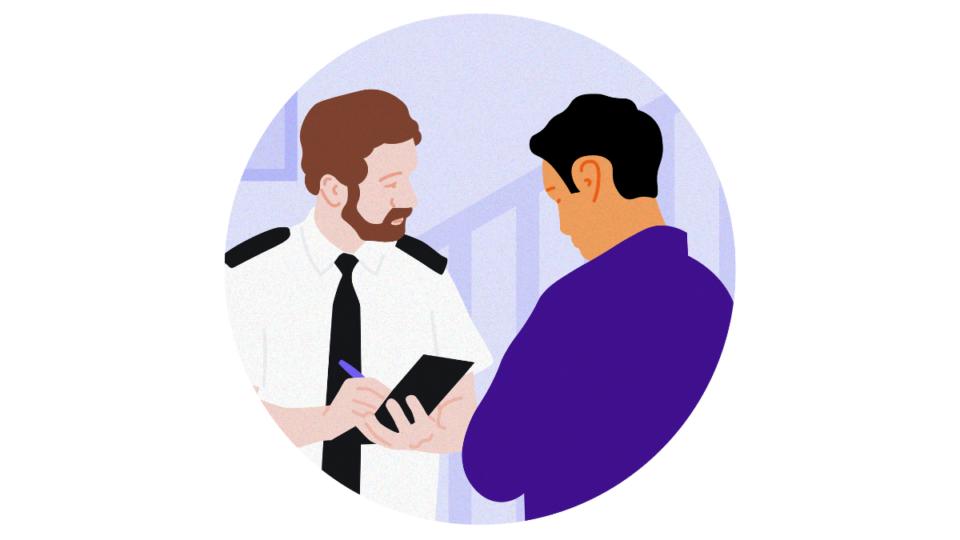 A police officer holding a pen and a notepad, talking to a man wearing a purple shirt.