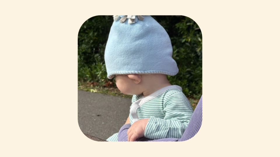 Baby Jonah wearing a blue hat, and a stripy top, facing away from the camera.