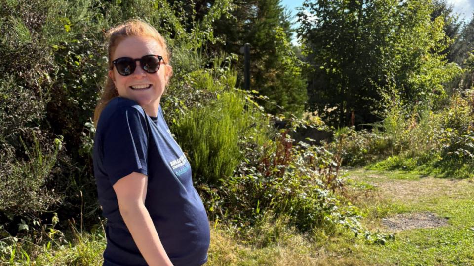 Chloe outdoors wearing sunglasses on a sunny day, smiling at the camera.