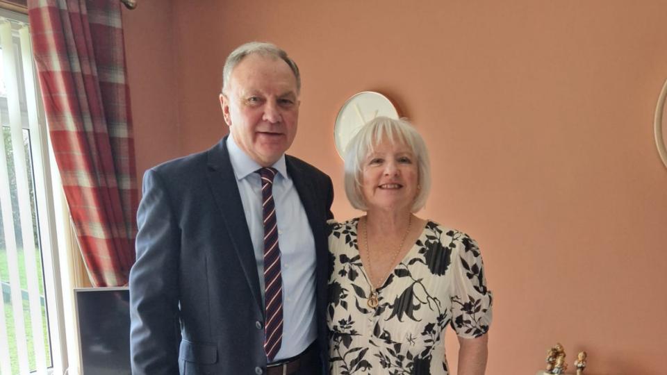 Marjorie and Ian, standing beside each other smiling at the camera
