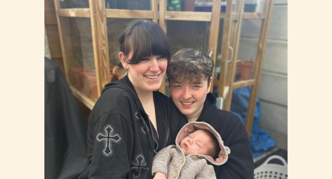 Lilly and James smiling at the camera, holding Theo.