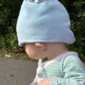 Baby Jonah wearing a blue hat, and a stripy top, facing away from the camera.