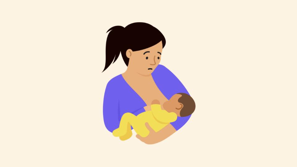 Worried mum, with her hair in a ponytail, holding her baby.