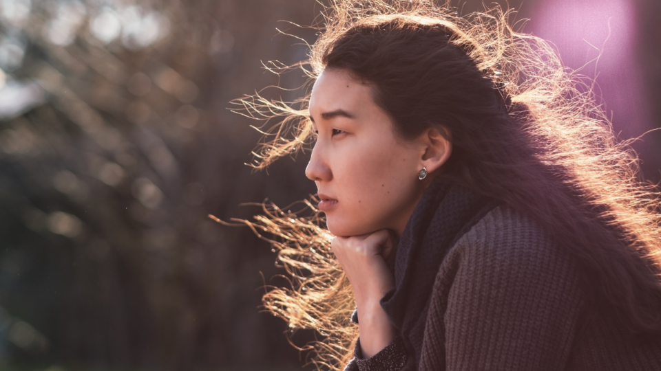 Lady wearing a black coat, sitting outdoors.