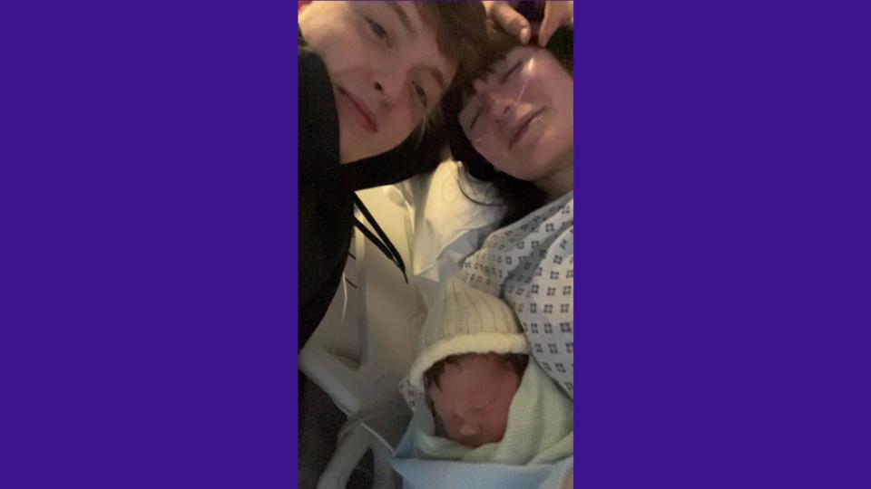 Lilly lying in hospital with Theo on her chest, and James smiling at the camera.