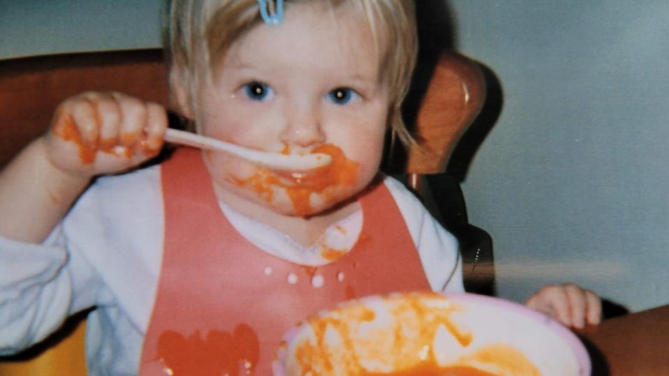 Sue's daughter eating a bowl of red soup, with food all around her mouth.