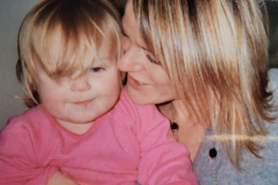 Sue with her daughter sitting on her lap, wearing a pink top.