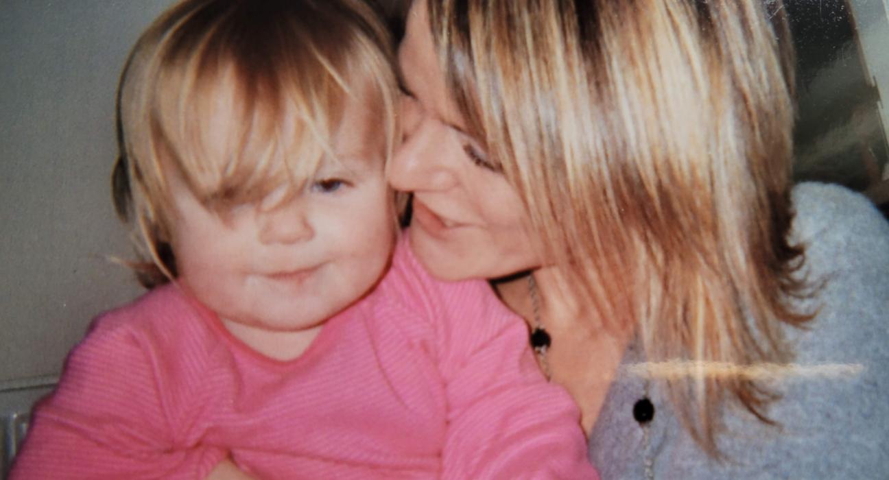 Sue with her daughter sitting on her lap, wearing a pink top.