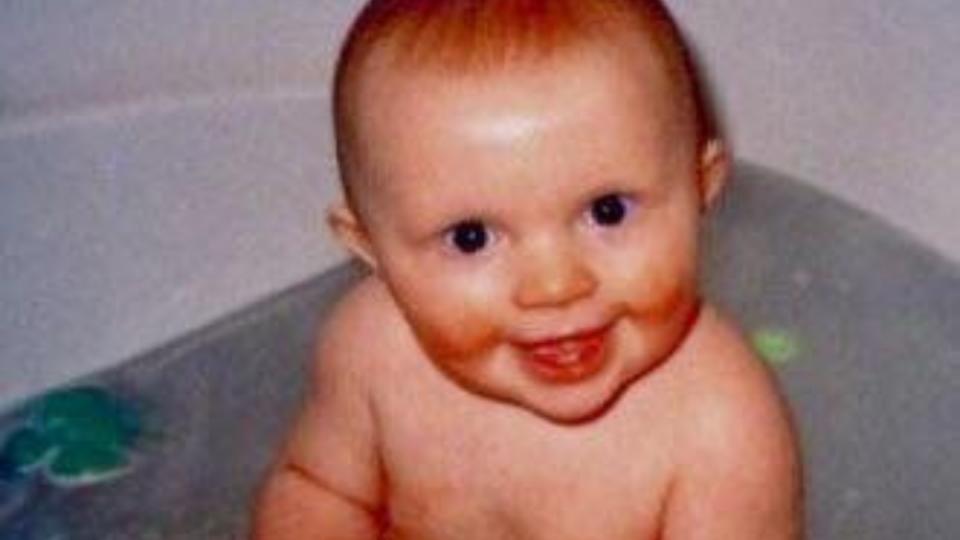 Kirsty's brother, Finlay, in the bath, smiling at the camera.