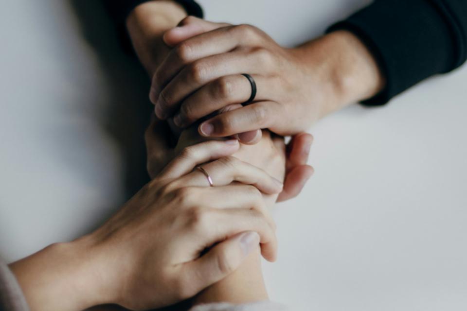 Two people's hands clutching each other over the table.