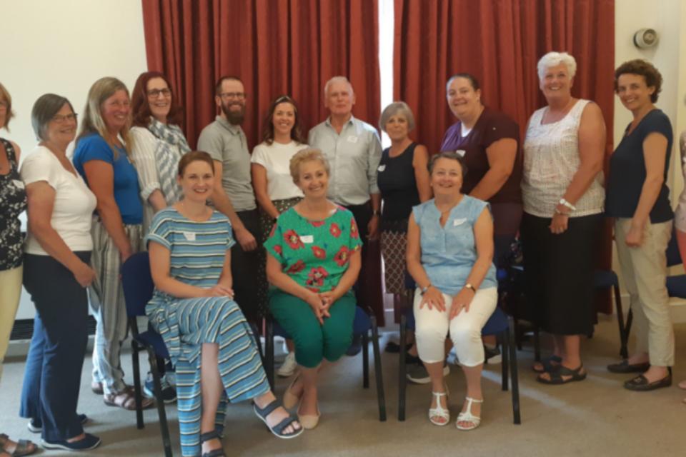 Group of befrienders, some sitting and some standing, all smiling at the camera.
