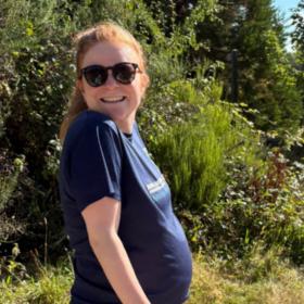 Chloe outdoors wearing sunglasses on a sunny day, smiling at the camera.