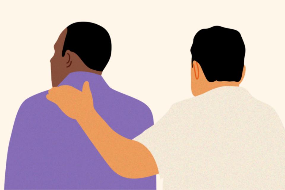 Two men with their back to us. One man has a supportive arm around the other.