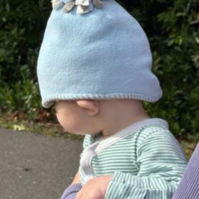 Baby Jonah wearing a blue hat, and a stripy top, facing away from the camera.