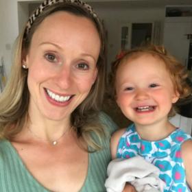 Laura and Amy smiling at the camera. Amy is wearing a flue top and has a happy face and red hair.