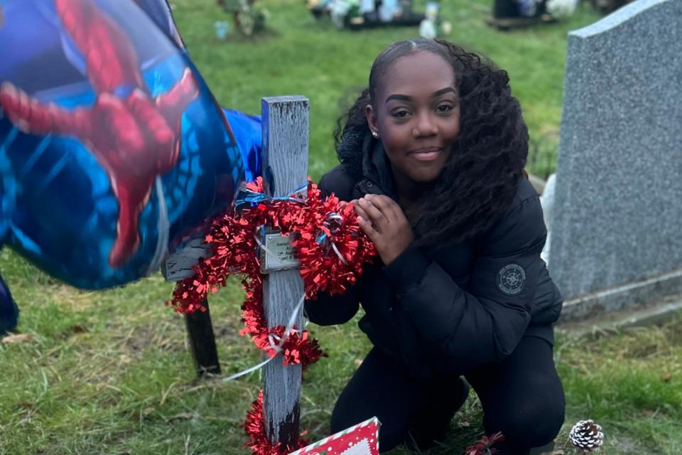 Tee at Azaiah's grave. There is a cross with red tinsel wrapped around it.