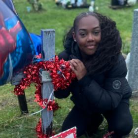 Tee at Azaiah's grave. There is a cross with red tinsel wrapped around it.