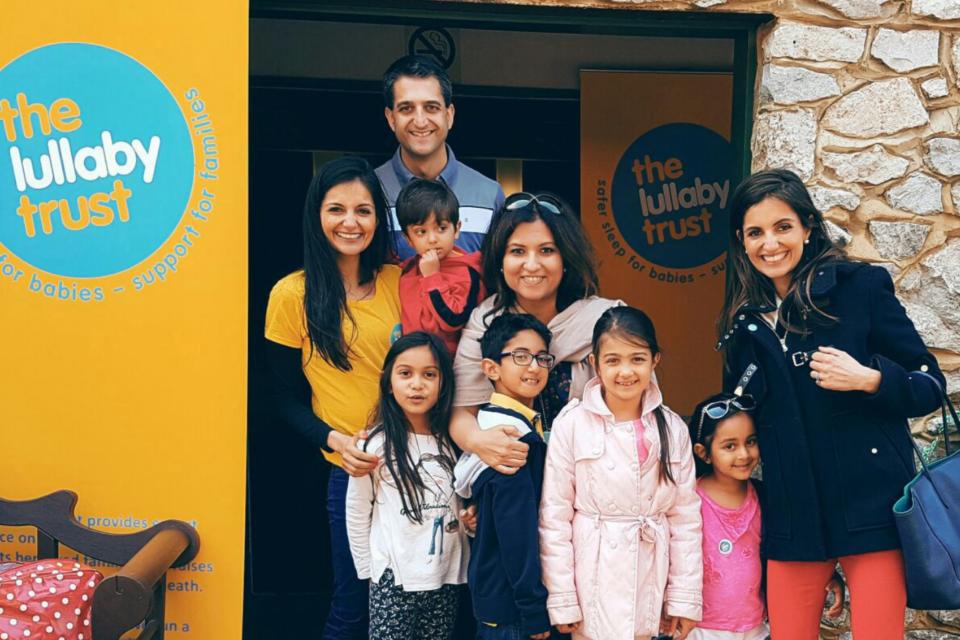 Siya and her family at an event, standing next to a yellow Lullaby Trust banner.