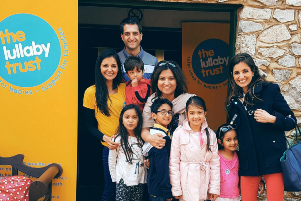 Siya and her family at an event, standing next to a yellow Lullaby Trust banner.