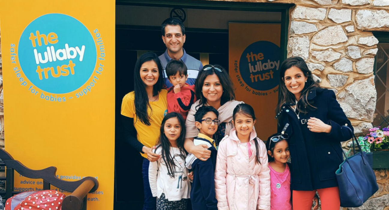 Siya and her family at an event, standing next to a yellow Lullaby Trust banner.