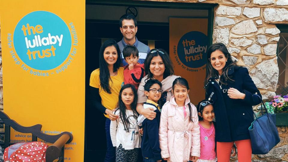 Siya and her family at an event, standing next to a yellow Lullaby Trust banner.