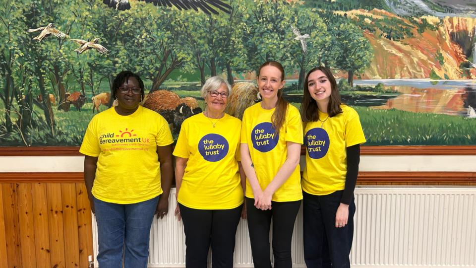 Four people wearing yellow Lullaby Tshirts, smiling at the camera.
