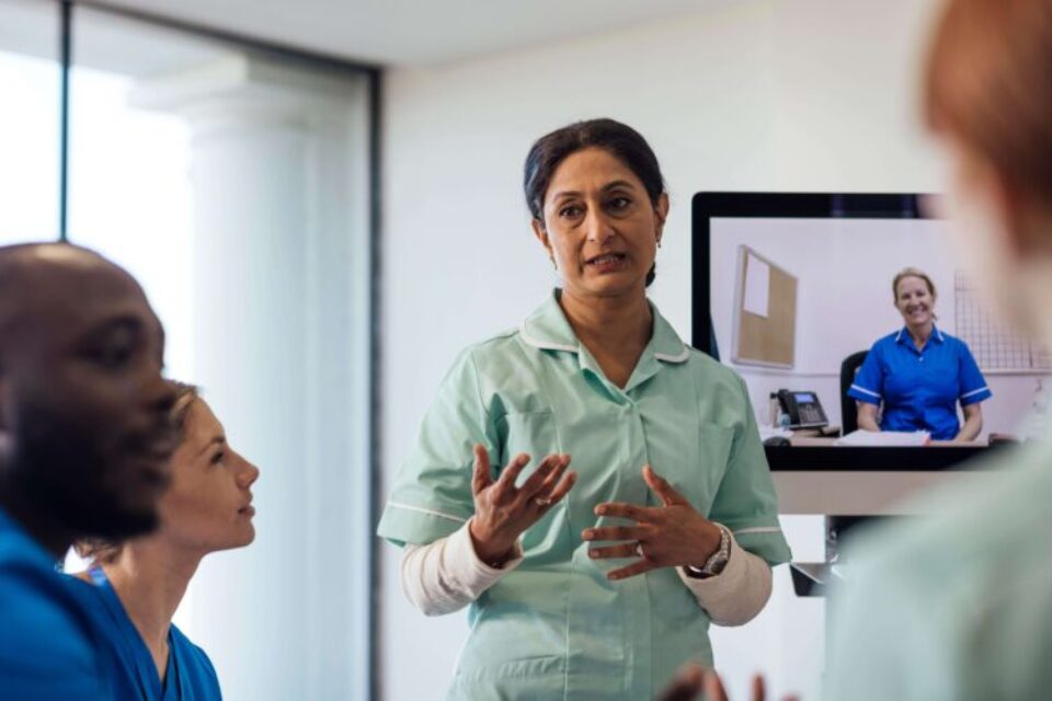 Health professionals sitting together talking, in a training setting.