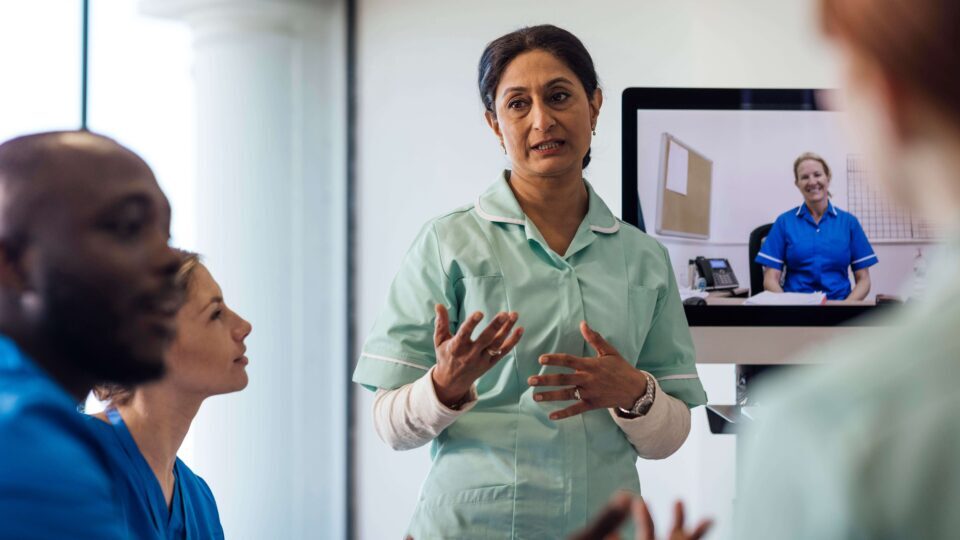 Health professionals sitting together talking, in a training setting.