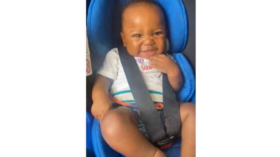 Azaiah smiling, sitting in a car seat.