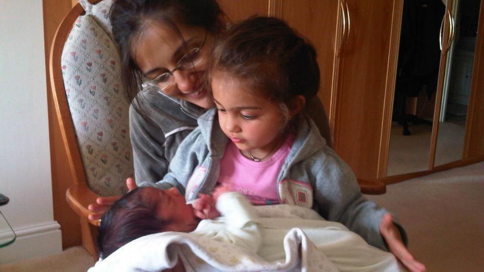 Siya with baby Krishan on her lap. Her mum is behind her.