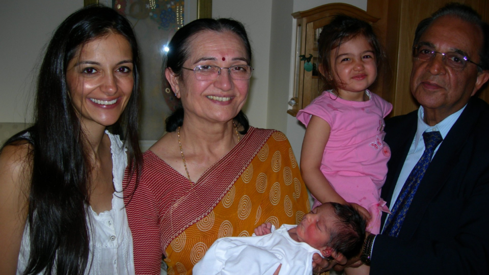 Siya and her family, holding baby Krishan. Siya is only a little girl and her mum is smiling at the camera.
