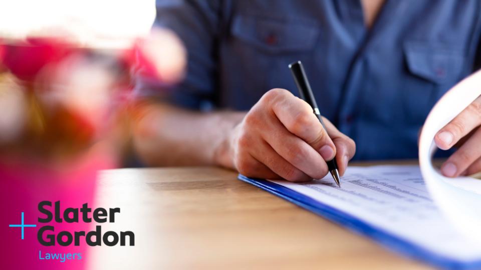 A person writing a will on a wooden desk