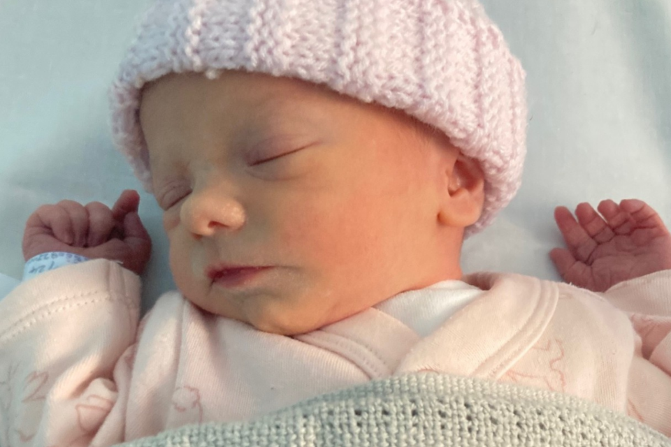Baby Phoebe asleep, with a blue blanket and light pink hat.