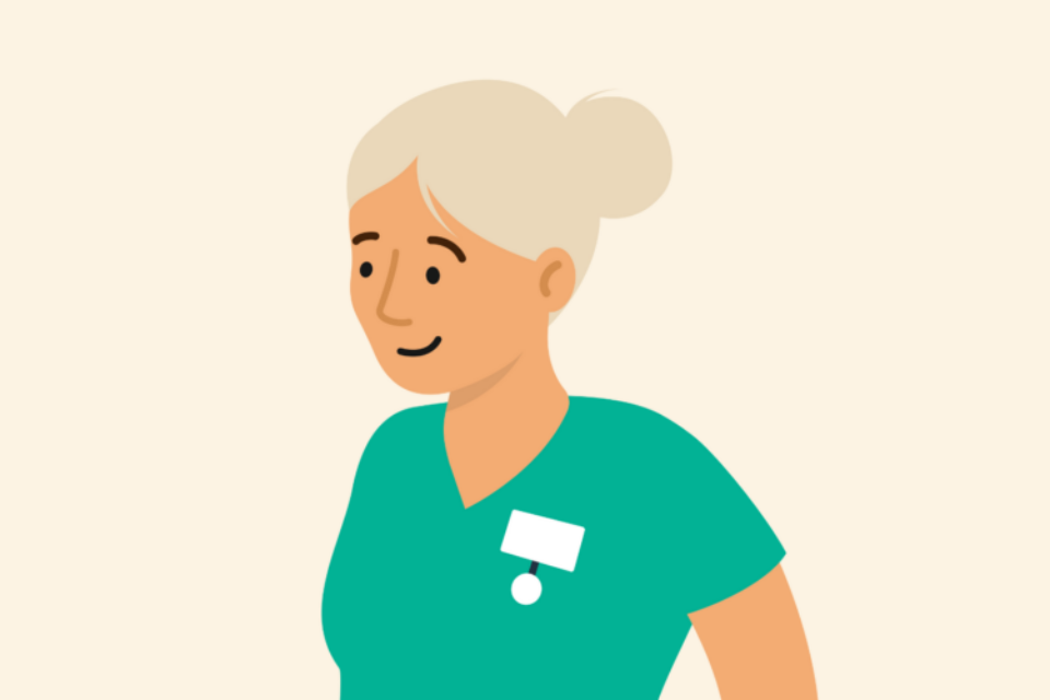 Health professional with grey hair wearing scrubs and smiling.