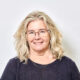 Professor Helen Ball headshot. She is smiling and wears a black t-shirt and gold necklace. She has blonde, wavy hair and blue eyes.