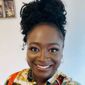Seyi wearing a pattenered shirt, smiling at the camera