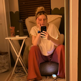 Jess sitting in her child's bedroom at night on a stool, with her chin resting on her hand.
