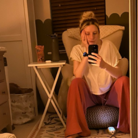 Jess sitting in her child's bedroom at night on a stool, with her chin resting on her hand.