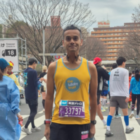 Abs in a Lullaby Trust running vest, at a running event.